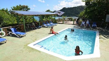 Una piscina al aire libre, sillones reclinables de piscina