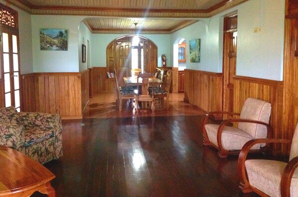 Um quarto espaçoso com painéis de madeira, uma área de refeições com mesa e cadeiras, e uma janela grande que oferece iluminação natural.