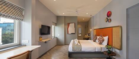 A modern hotel room with a large bed, a desk, and a television.