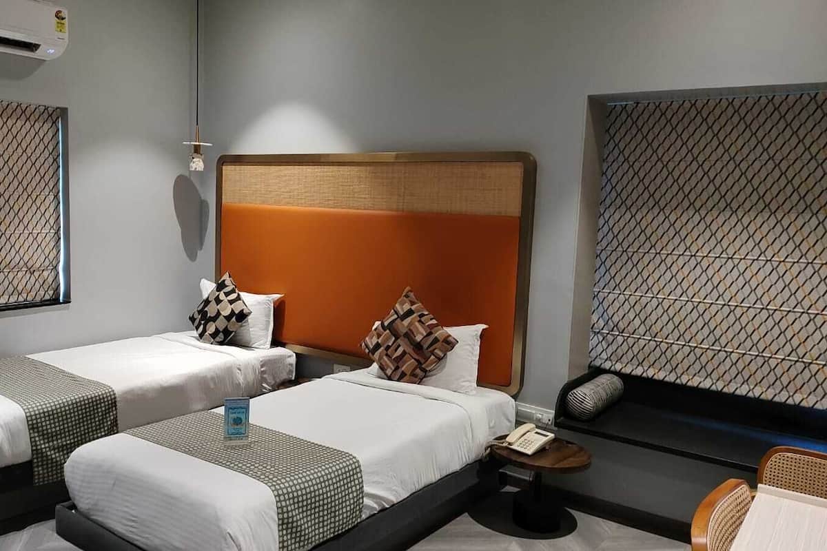 Habitación de hotel con dos camas, una mesita, una silla y un teléfono instalado en la pared.