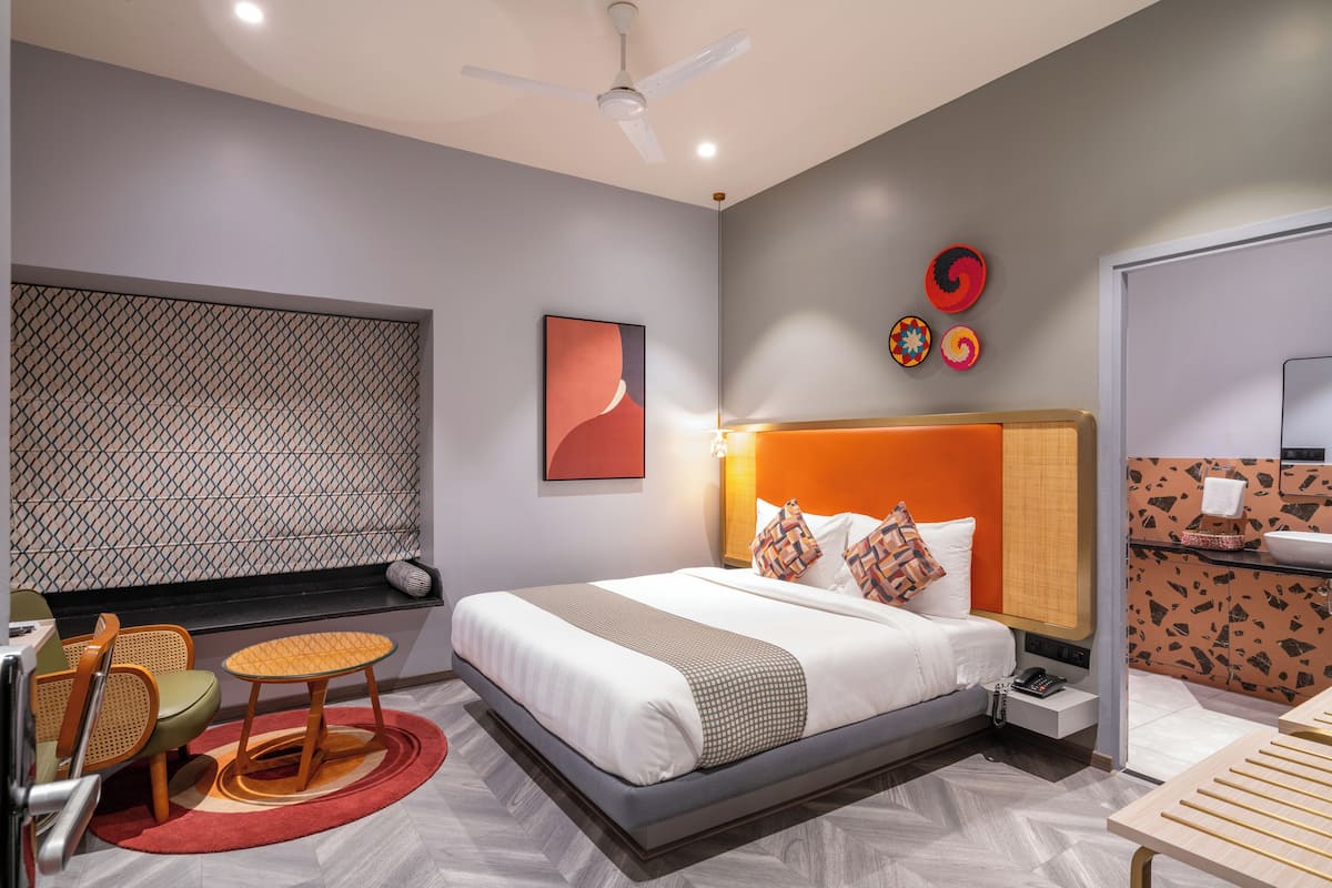 Una habitación de hotel moderna con cama, zona de estar y baño.