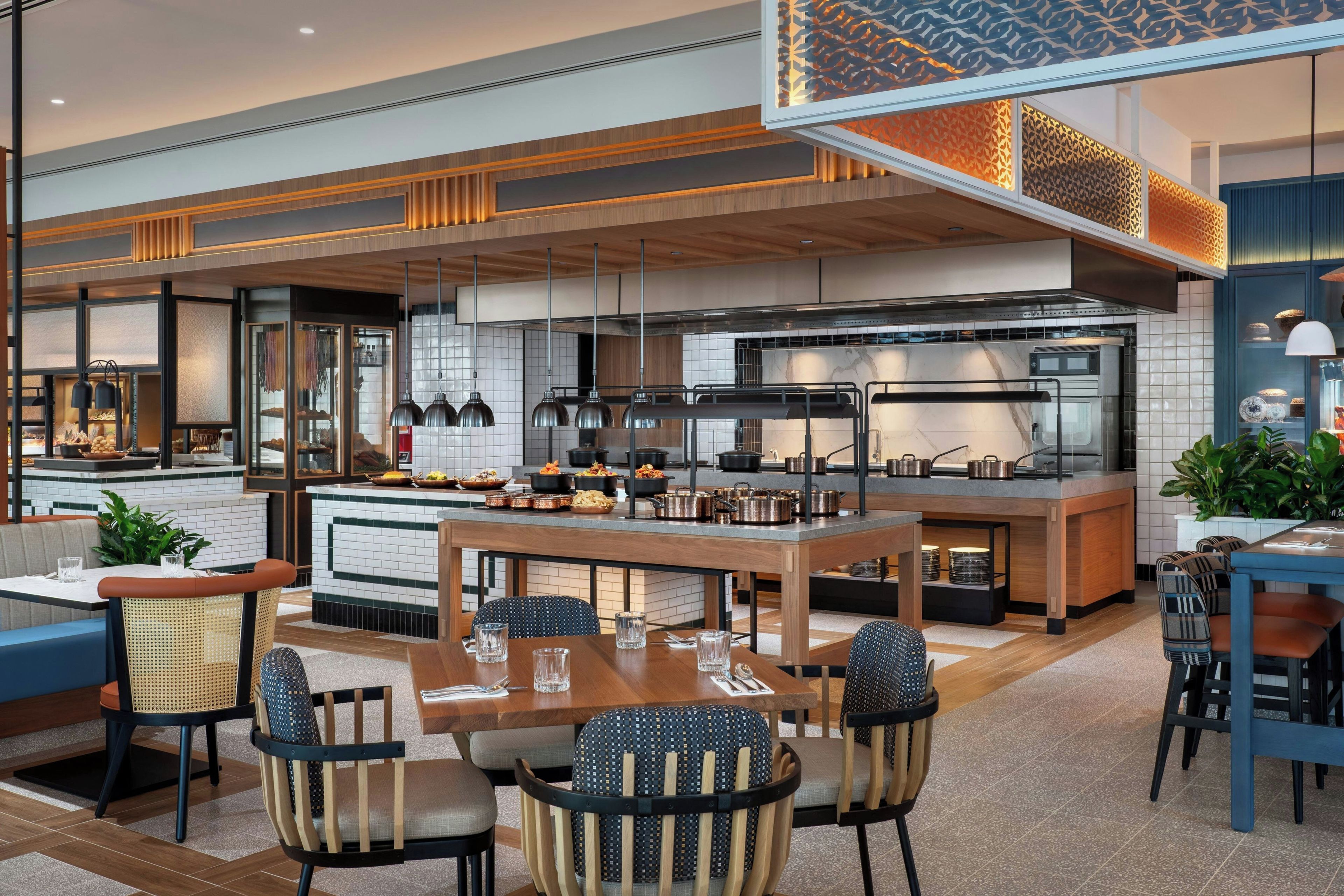 Una cocina moderna con una isla central, comedor con sillas y una zona de bar con taburetes.