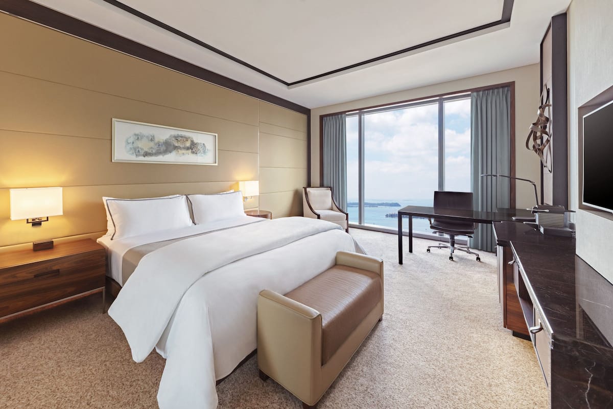 Une chambre d’hôtel avec un grand lit, un bureau, une chaise et un téléviseur.
