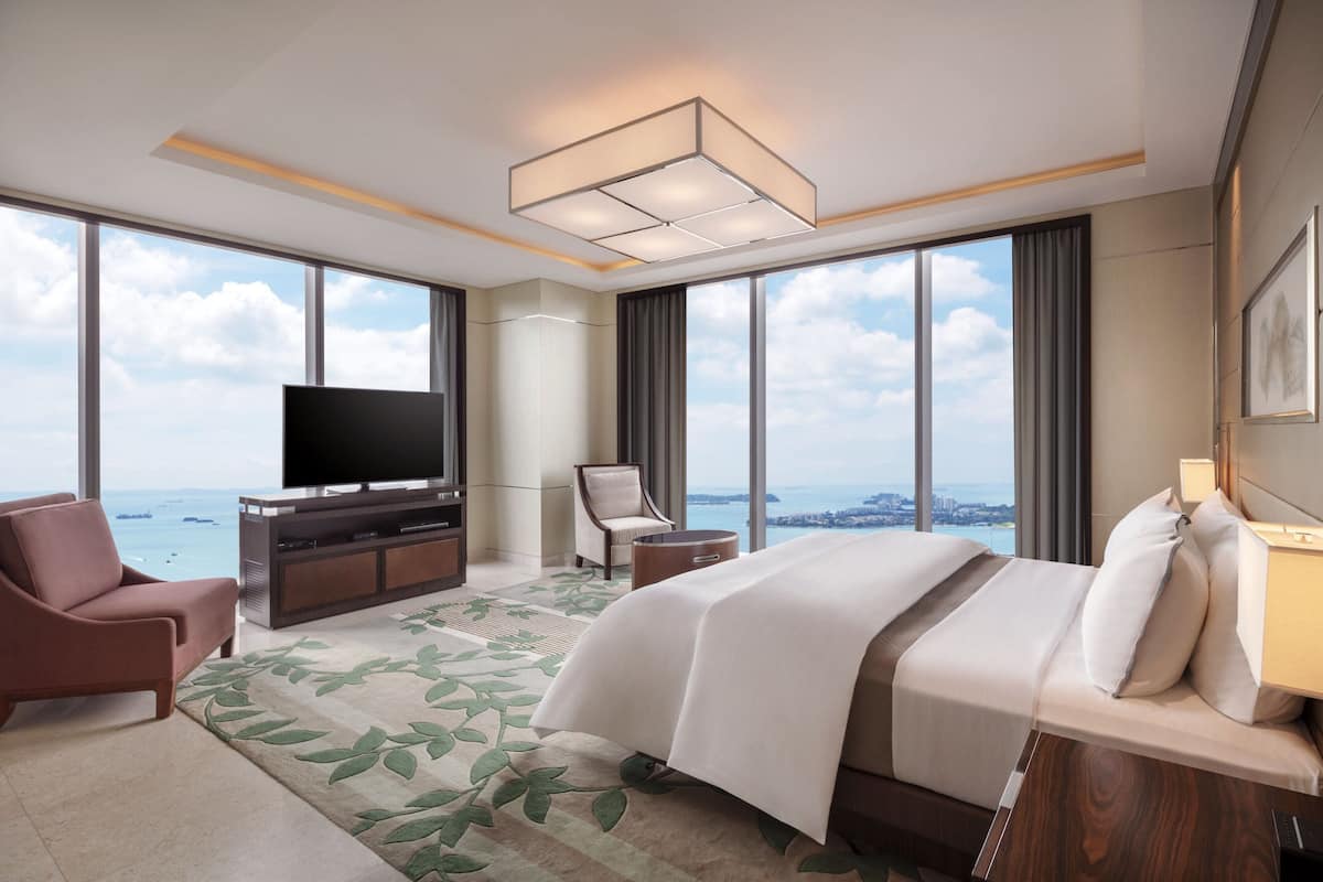 Une chambre d’hôtel moderne avec un grand lit, une télévision, un fauteuil et une vue sur la mer.