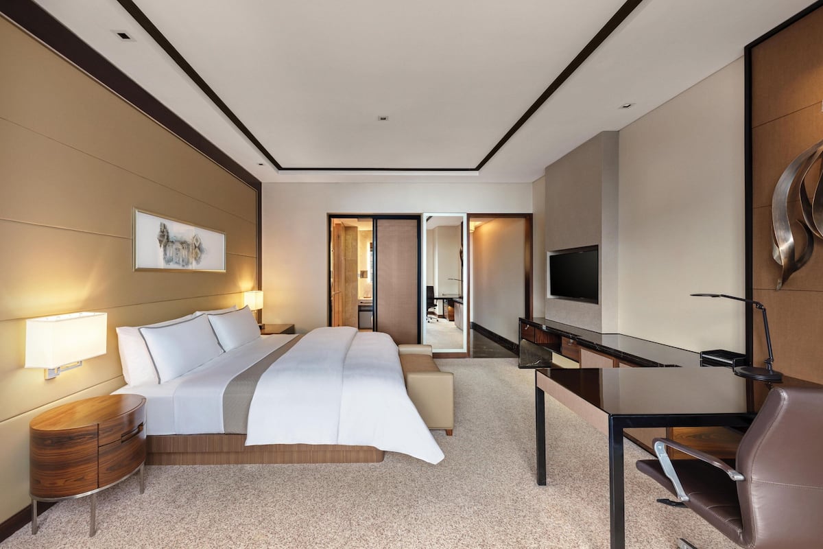Une chambre d’hôtel moderne, dotée d’un grand lit, d’un bureau et d’une télévision.