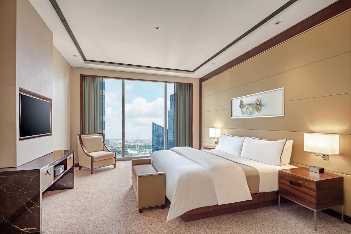 Une chambre d’hôtel avec un grand lit, une télévision, un bureau, une chaise et une vue sur la ville.