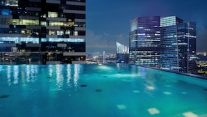 Une piscine sur le toit offrant une vue sur le paysage urbain, avec des bâtiments modernes et un pont en arrière-plan.