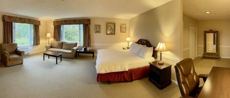 Habitación de hotel con una cama grande, un sofá, una silla, un escritorio y una chimenea.