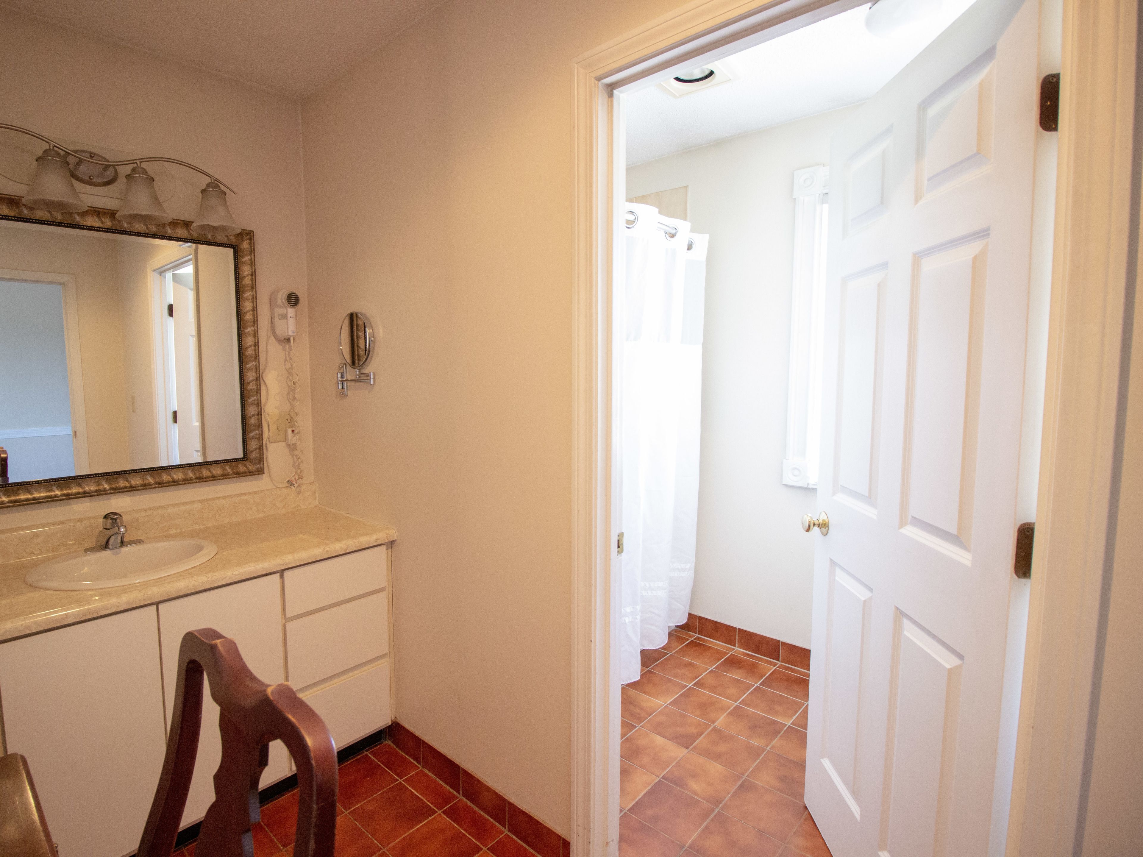 A bathroom with a sink, mirror, and shower curtain.
