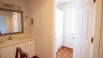 Un baño con lavamanos, espejo y cortina de ducha.