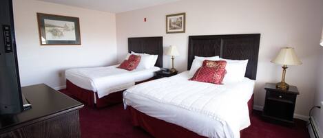 A hotel room with two beds, a TV, and a desk.
