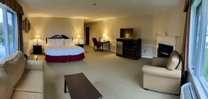 A hotel room with a bed, a desk, a chair, a sofa, and a fireplace. - The Lucerne Inn (Holden)