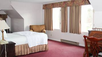A hotel room with a bed, a chair, a desk, and a telephone.