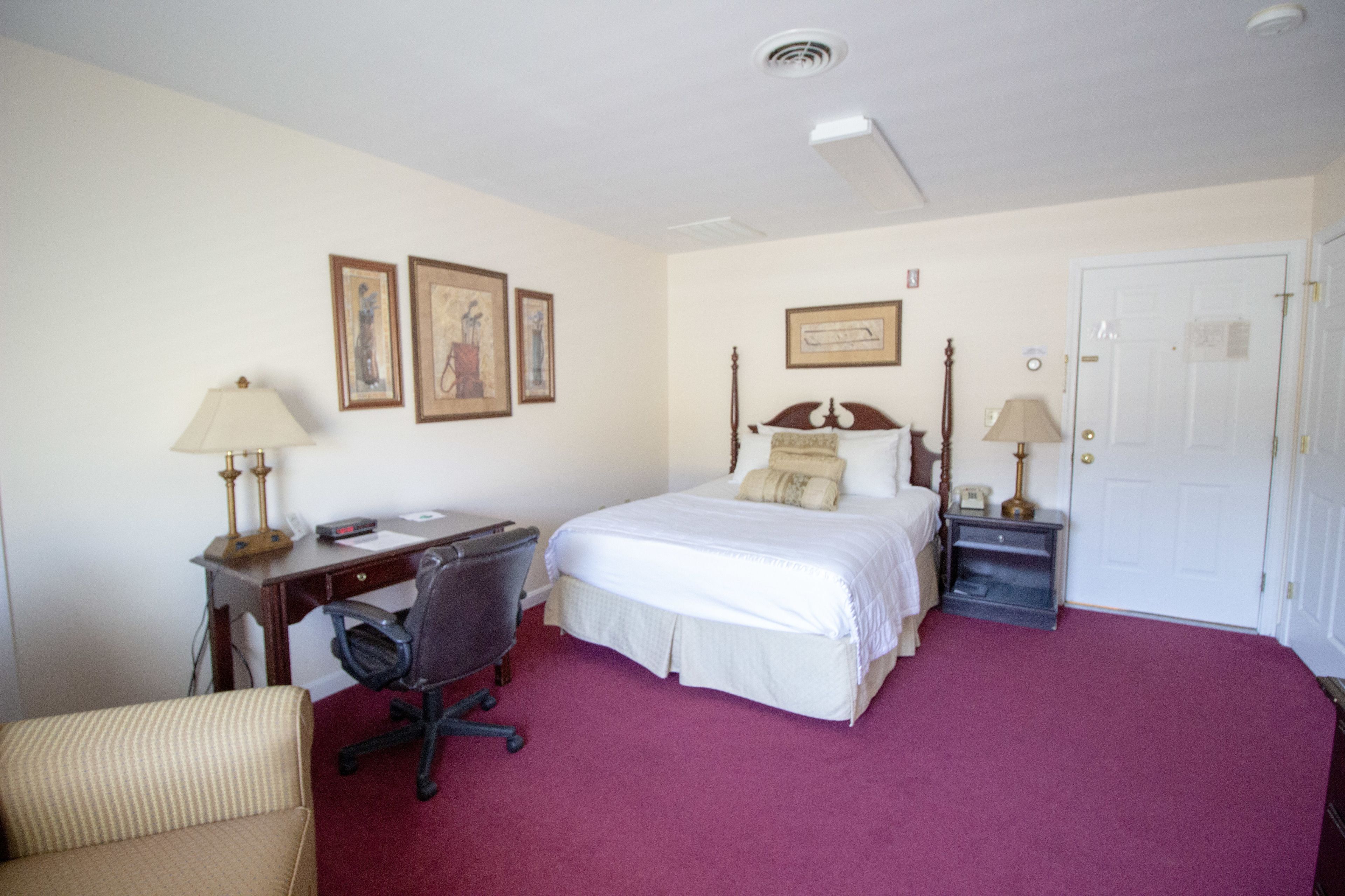 Ein Hotelzimmer mit Bett, Schreibtisch, Stuhl und zwei Nachttischen.