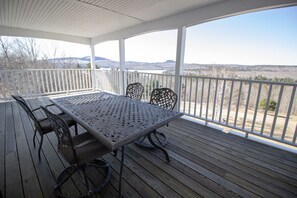 A covered outdoor patio with a table and chairs, overlooking a scenic landscape. - The Lucerne Inn (Holden)