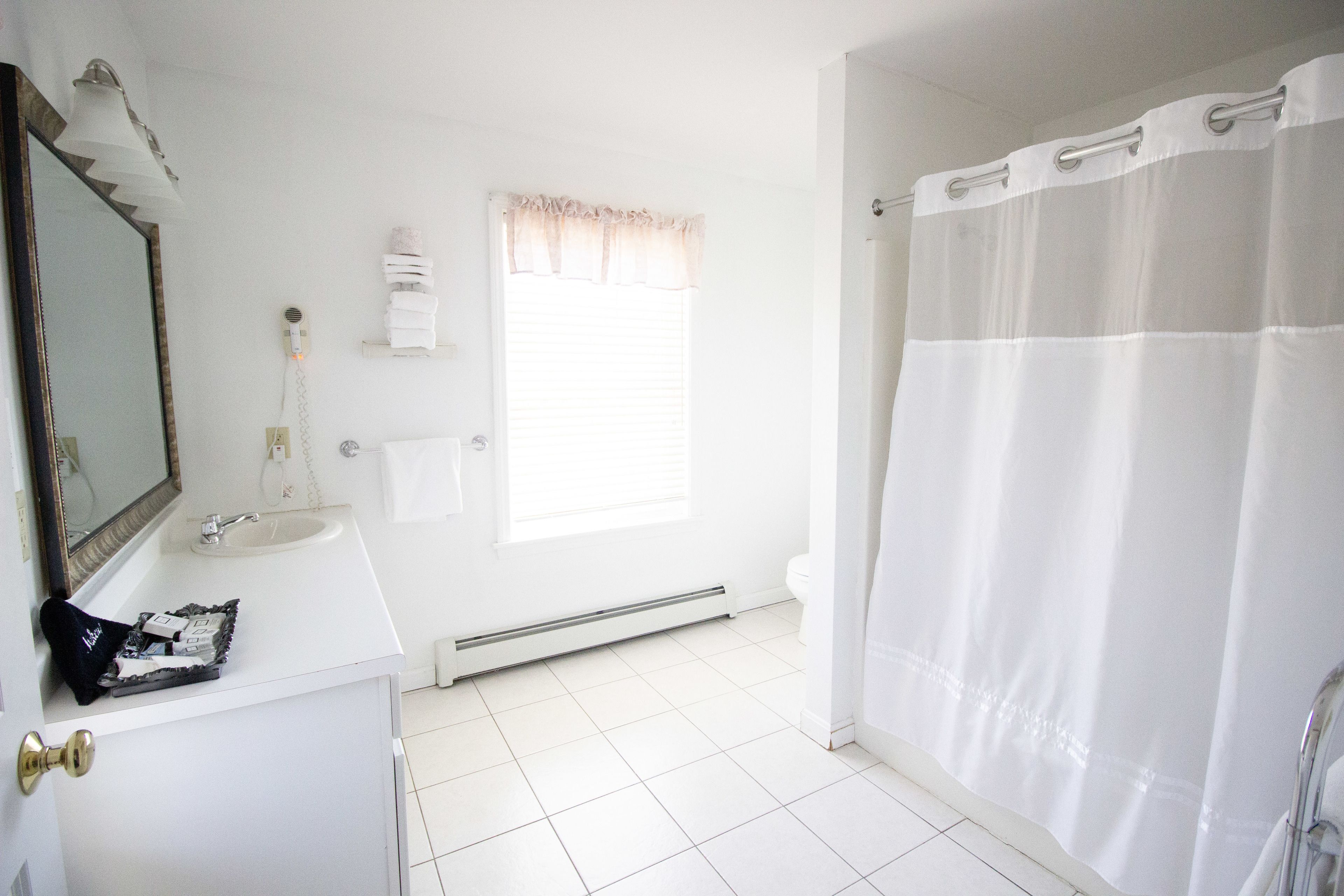 Une salle de bain avec un lavabo blanc, un miroir et un rideau de douche.