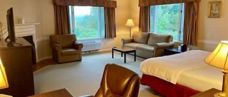 Una habitación de hotel con una cama, dos sillones, un sofá, un escritorio y un televisor.