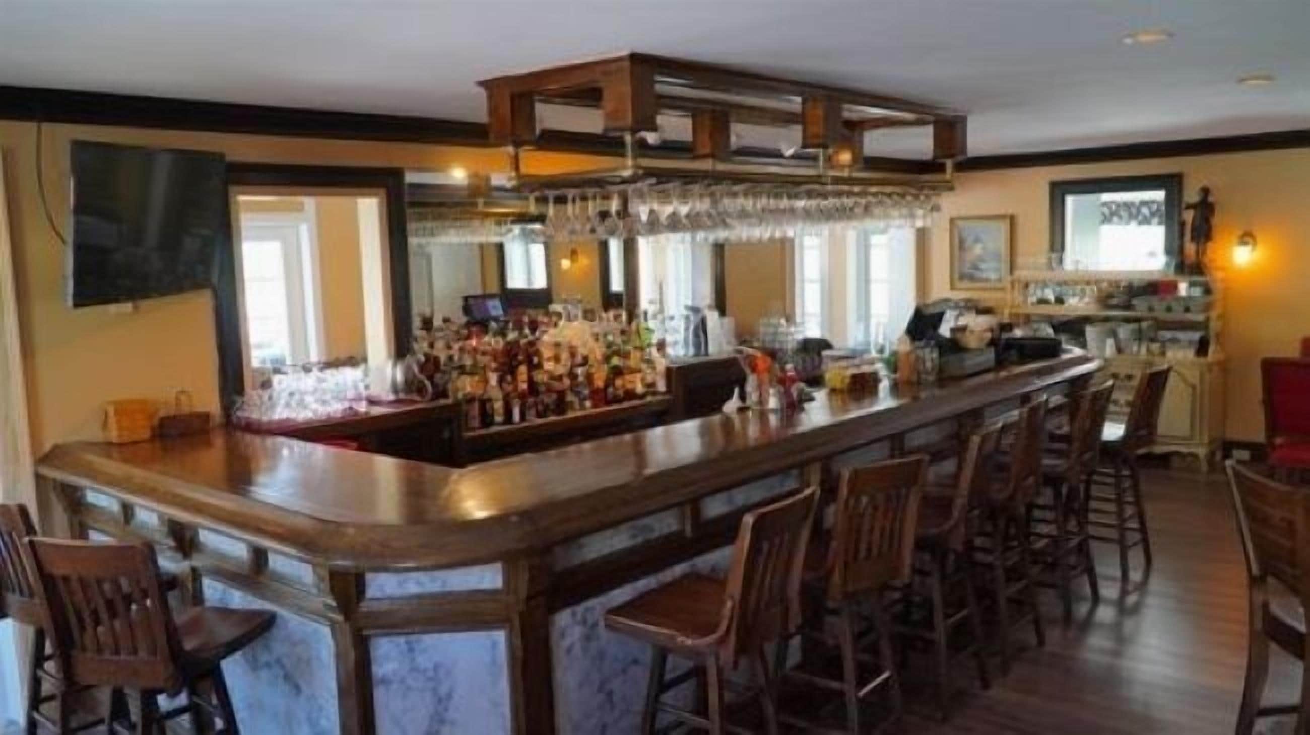 Un espace bar doté d’un long comptoir, de nombreux tabourets et d’une variété de bouteilles et de verres.