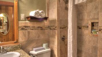 A bathroom with a sink, toilet, and shower area.