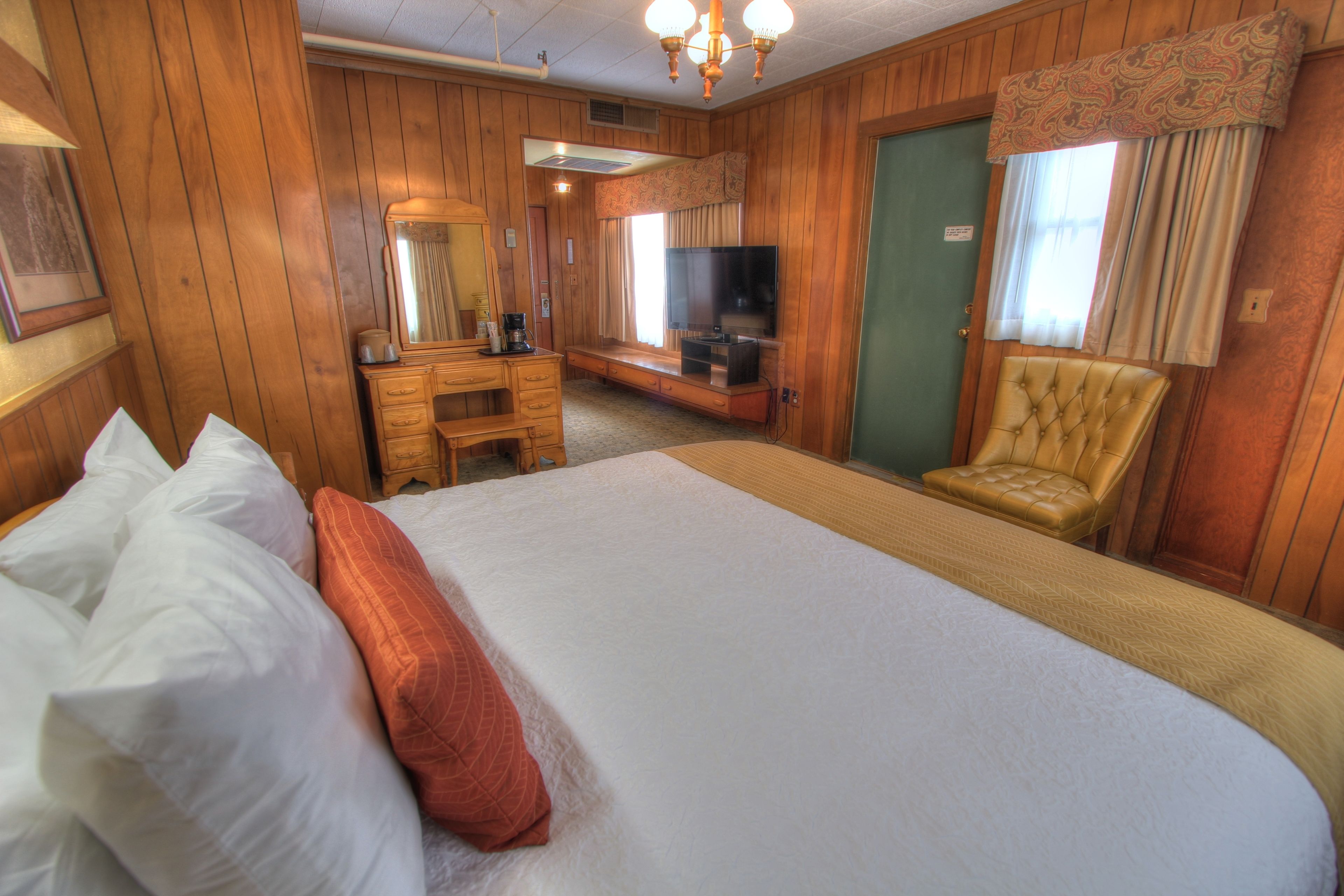 Ein Hotelzimmer mit einem großen Bett, einem Fernseher, einem Schreibtisch und einem Sessel.