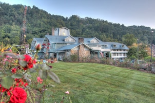 A large house with a stone facade, multiple chimneys, and a well-maintained lawn.