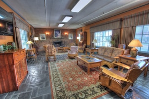 A cozy living room with a fireplace, comfortable seating, and a large rug.