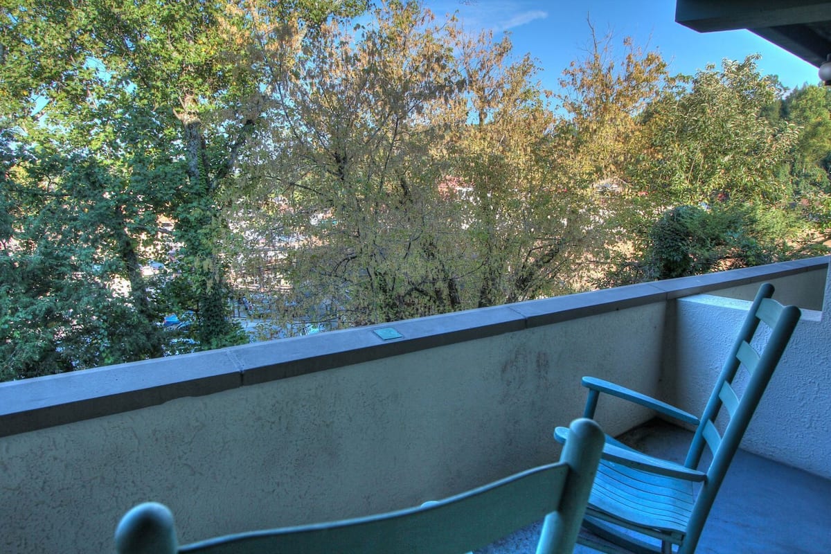 A balcony with a view of trees and a building in the background.