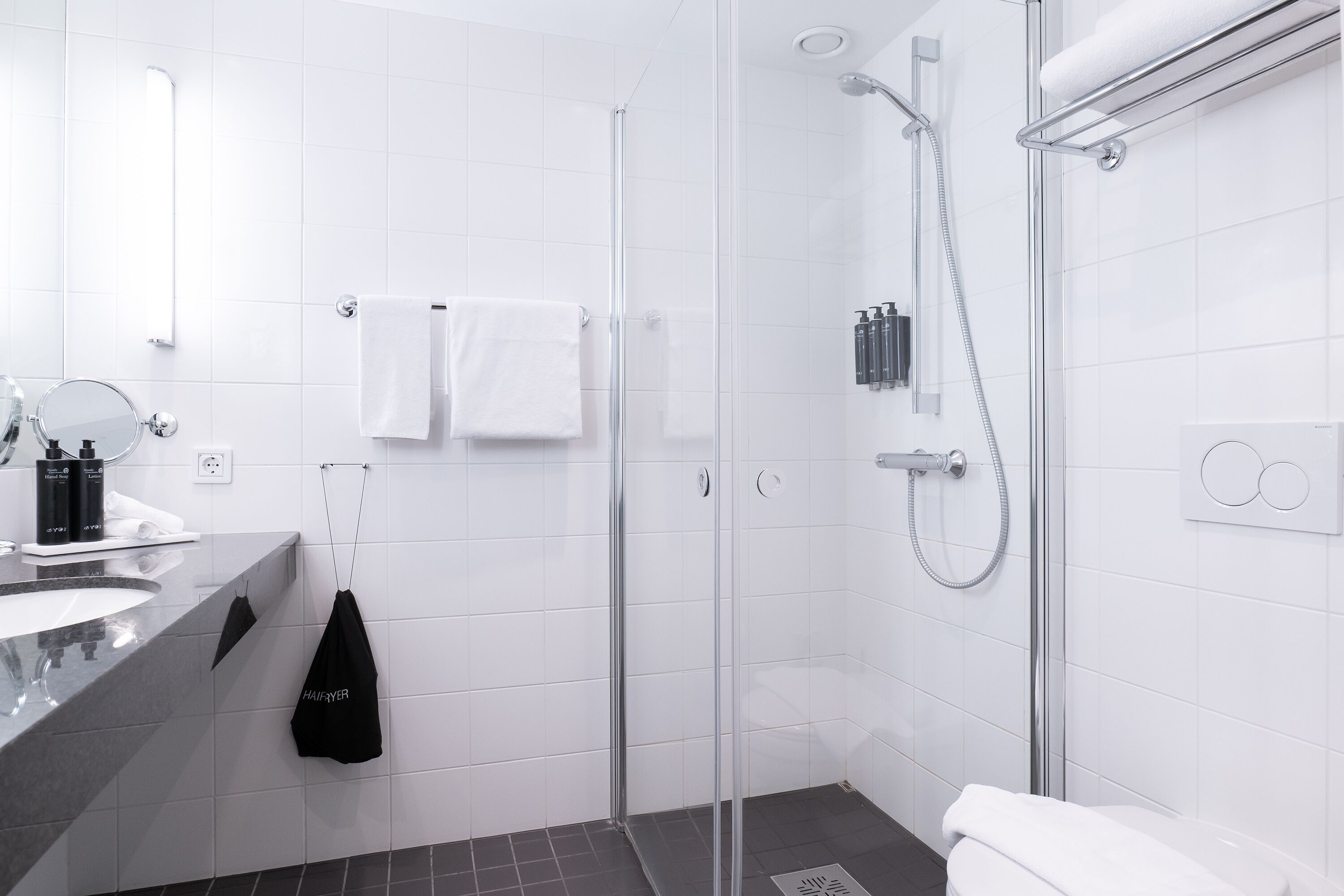 Un baño moderno con cabina de ducha de vidrio, un lavabo blanco y un espejo.