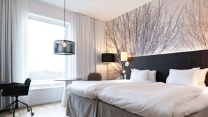 A hotel room with a large bed, a desk, and a chair. There is a window with curtains, a wall-mounted lamp, and a ceiling light. - Best Western Plus Park City Lund (Lund)