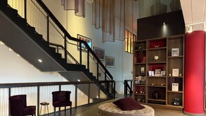 A modern lobby with a staircase, a round seating area, and a bookshelf. - Best Western Plus Park City Lund (Lund)