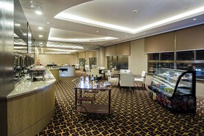 A hotel lobby with a buffet area, seating, and a refrigerated display case. - Millennium Hotel Fuqing (Fuzhou)