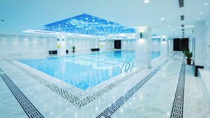 A large indoor swimming pool with a blue ceiling, surrounded by white marble walls and floors. - Millennium Hotel Fuqing (Fuzhou)