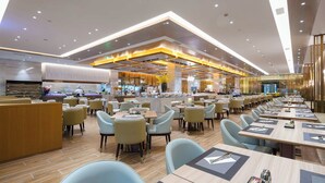 A modern restaurant with a long counter, multiple seating areas, and a bar. - Millennium Hotel Fuqing (Fuzhou)