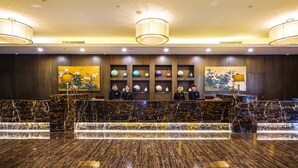 A reception area with a marble counter, multiple chandeliers, and decorative vases on shelves. - Millennium Hotel Fuqing (Fuzhou)