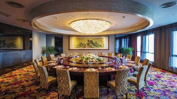 A conference room with a round table, chairs, a chandelier, and artwork on the walls.