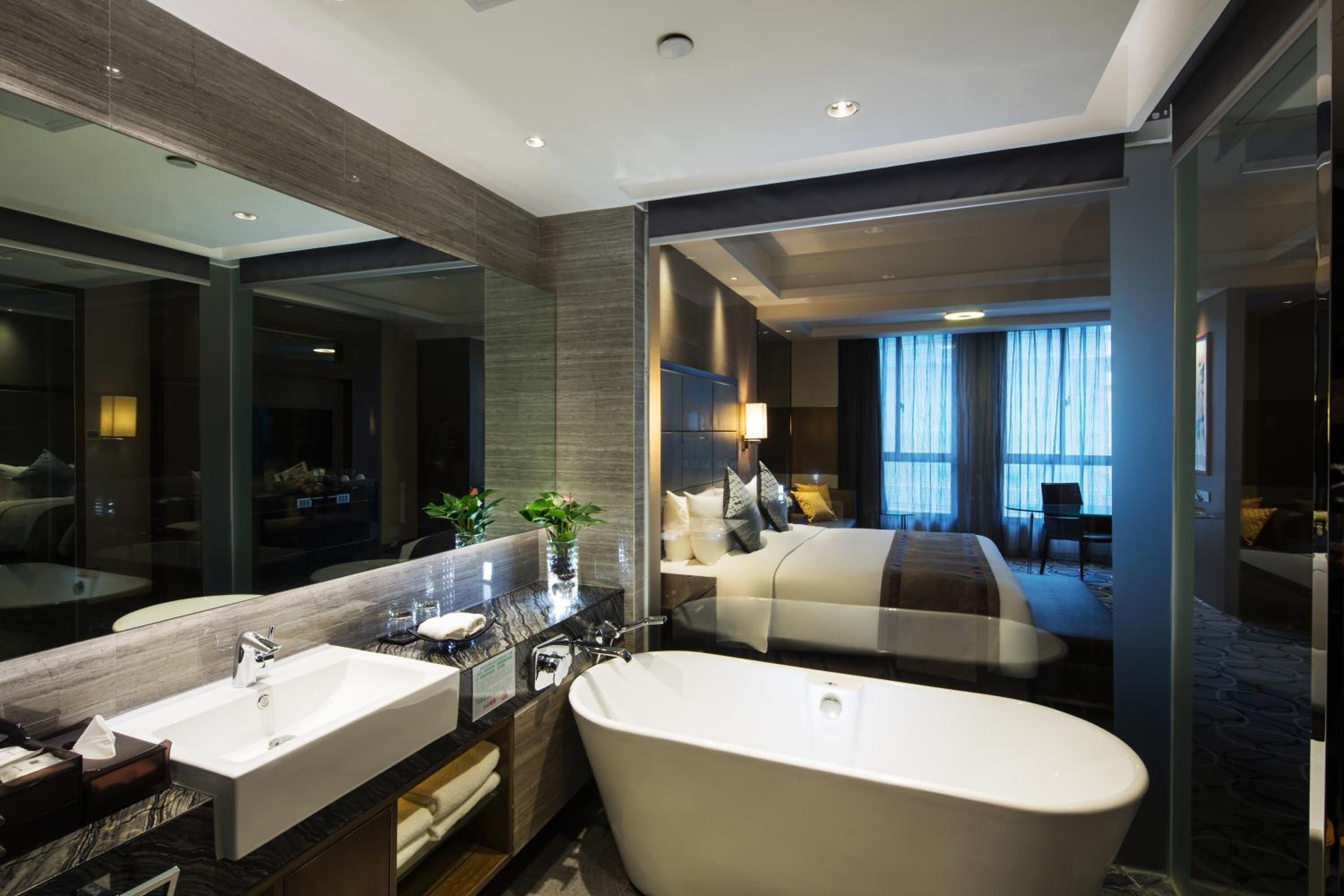 Un baño de hotel moderno con una bañera grande, lavamanos dobles y un espejo amplio.