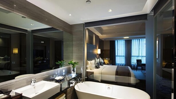 A modern hotel bathroom with a large bathtub, a double sink, and a large mirror. - Millennium Hotel Fuqing (Fuzhou)