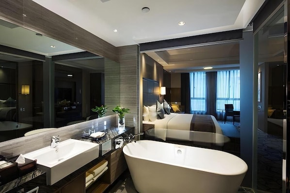 A modern hotel bathroom with a large bathtub, a double sink, and a large mirror.