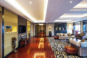 A spacious hotel lobby with a long corridor, a seating area with a patterned rug, and a wall-mounted television. - Millennium Hotel Fuqing (Fuzhou)