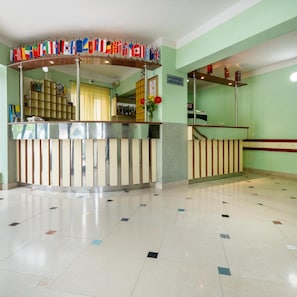 A reception area with a counter, a staircase, and a wall with flags. - Hotel Adria (Neum)