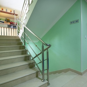 A staircase with metal handrails, a green wall, and a sign indicating room number 101-305. - Hotel Adria (Neum)