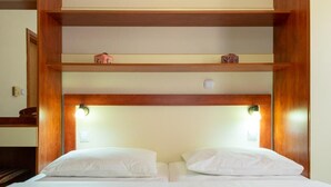 Een tweepersoonsbed met een houten hoofdbord, twee nachtkastjes en een bijzettafeltje.