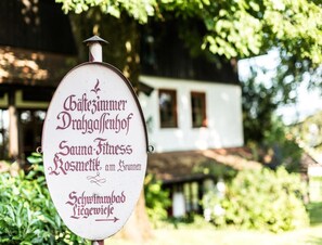 A sign for a spa and fitness center named "Häftelezimmer Dr.-Gallenhof" with a rustic building in the background. - Salzburg Hotel Holznerwirt (Eugendorf)