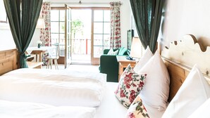 Slaapkamer met een groot bed, een houten hoofdbord en uitzicht op een buitenruimte met een tafel en stoelen.