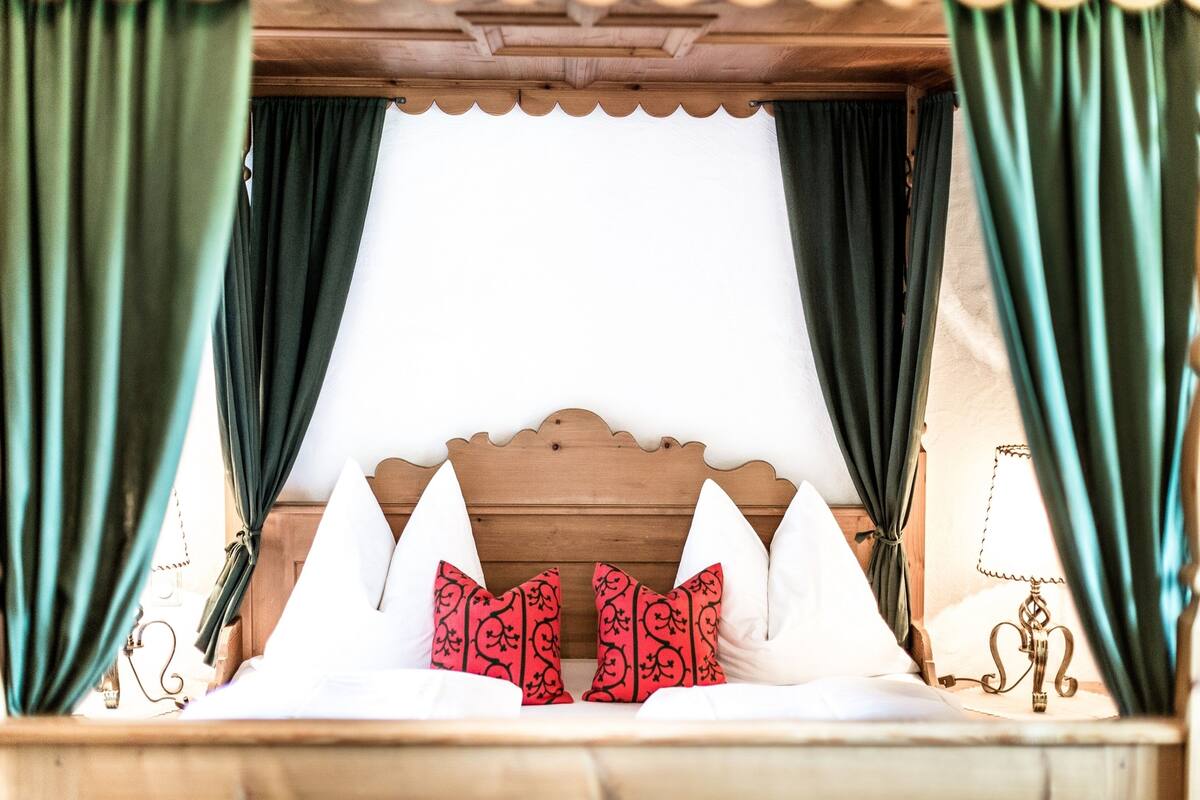 A bed with a wooden headboard, green curtains, and white bedding.