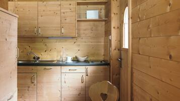 Una cocina compacta con armarios de madera, un lavamanos y una silla con forma de corazón.