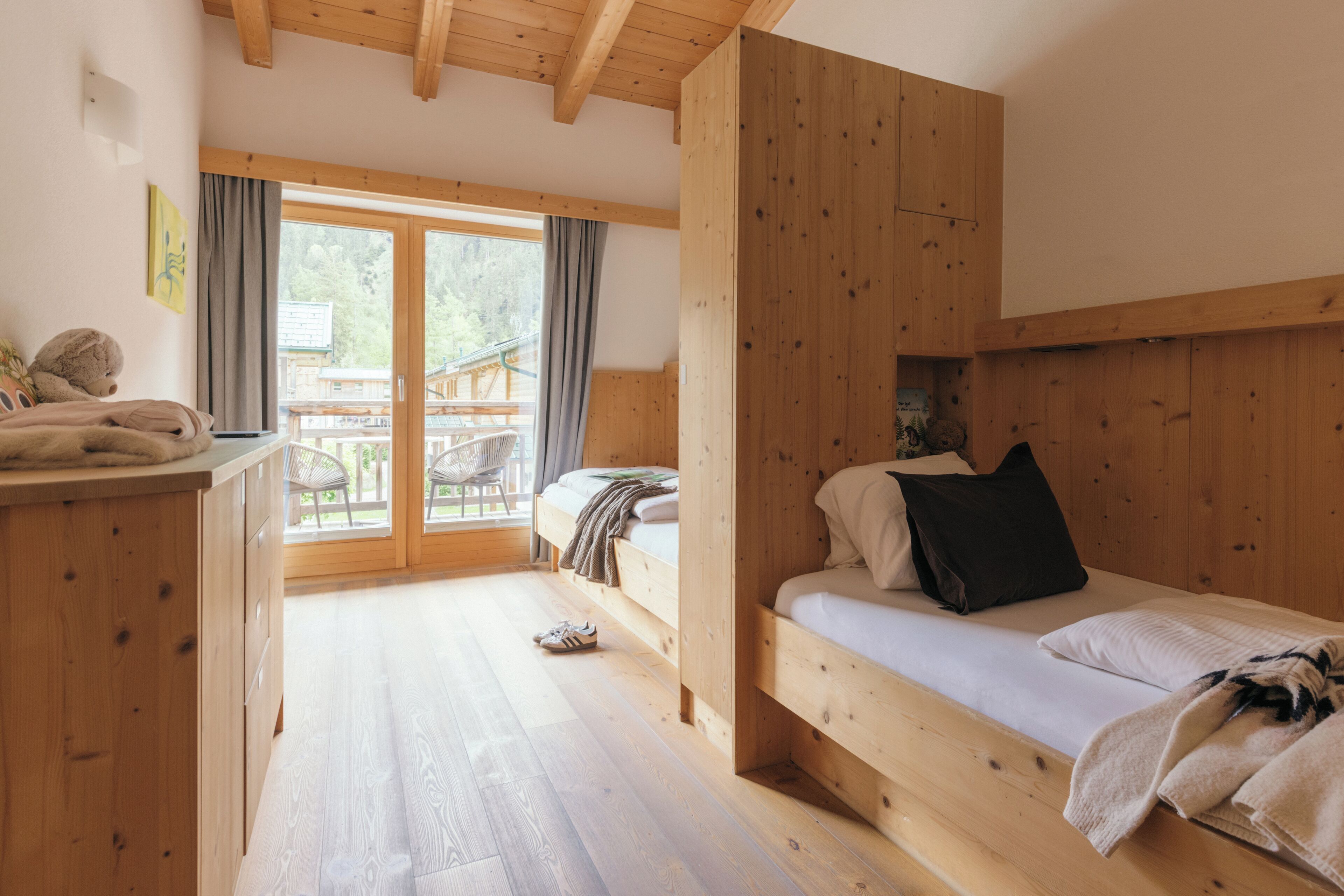 Habitación de cabaña de madera con literas, un escritorio y vistas al exterior.
