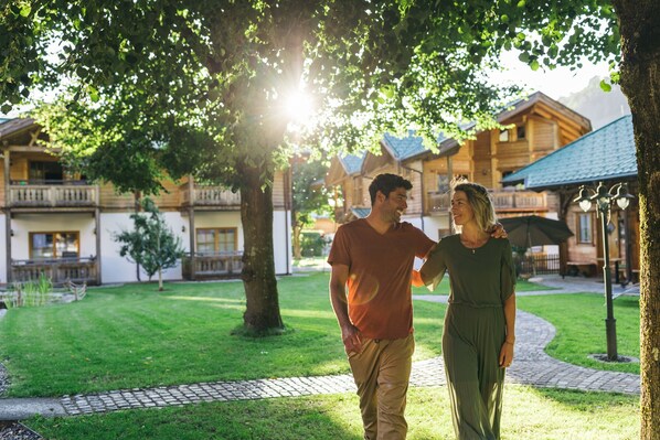 Una pareja caminando en un patio con edificios de madera al fondo.