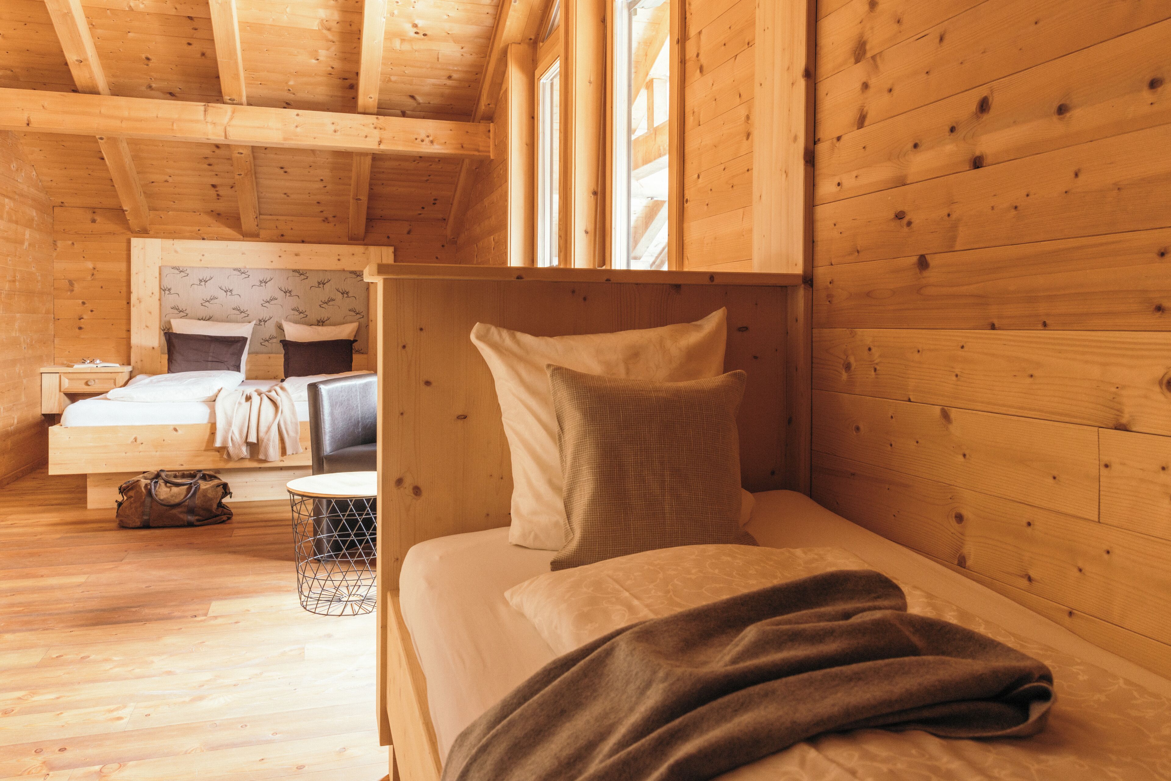 Ein Zimmer in einer Holzhütte mit einem Bett, einem kleinen Tisch und einem Fenster.