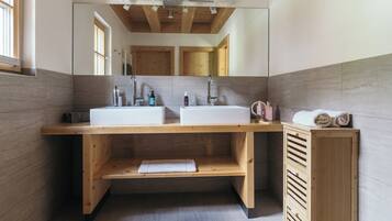 A modern bathroom with two sinks, wooden vanity, and a large mirror.